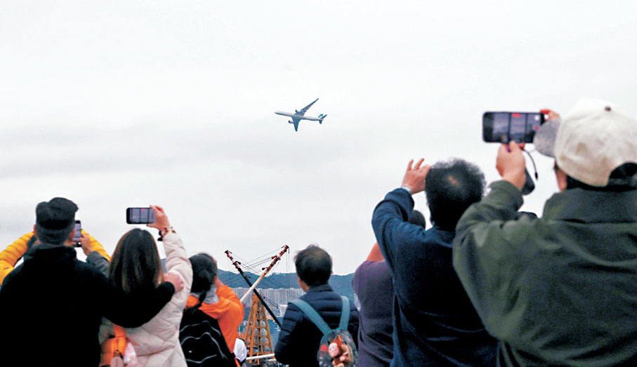 ●客機低飛掠過體育園上空,市民爭相舉機拍攝。香港文匯報記者郭木又 攝