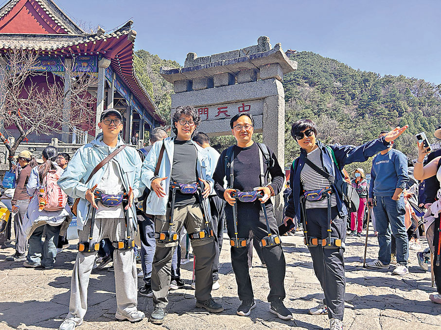 ●香港學生羅成鈞(左一)和任俊宇(左二)穿上登山助力機器人準備登泰山。香港文匯報山東傳真