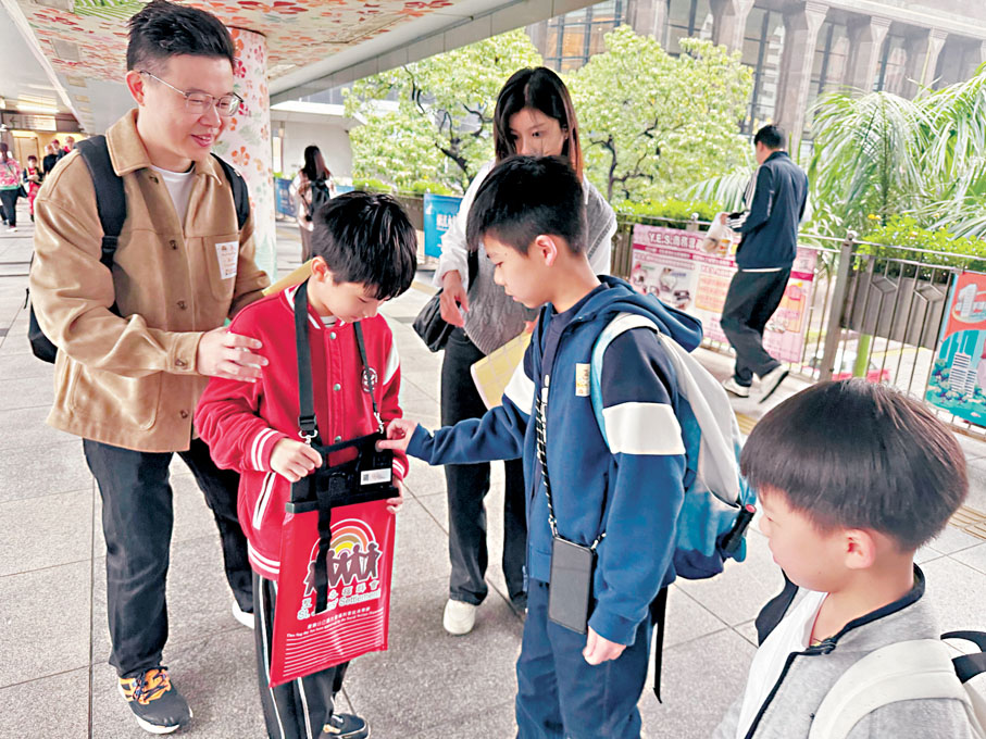●聖越(左二)最初顯得害羞,後鼓起勇氣和爸爸邀請市民買旗。 人才辦供圖