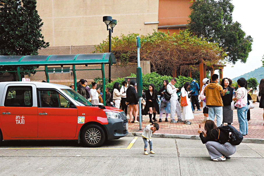 ●家長為小朋友打卡，似乎未有注意其身後有的士。香港文匯報記者萬霜靈  攝