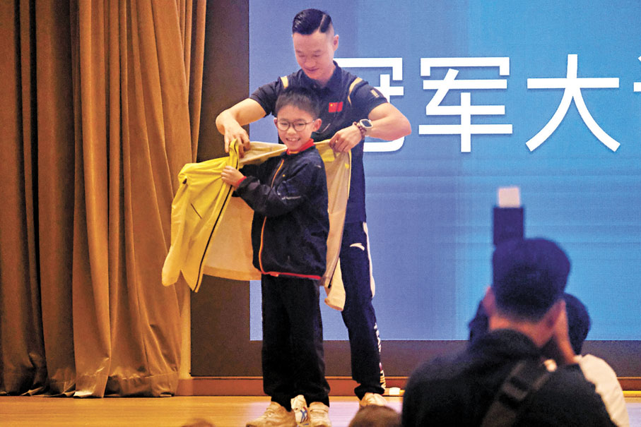●楊威為小二學生方一琛穿上其外套。香港文匯報記者涂穴 攝