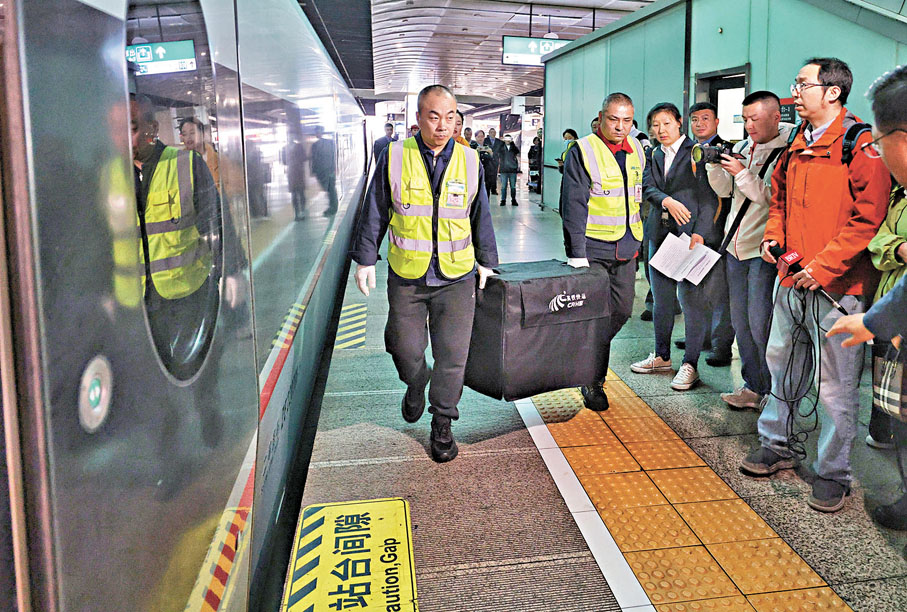 ●4月10日,北京南站,中鐵快運工作人員準備將裝有寵物的箱子運上列車。 中新社