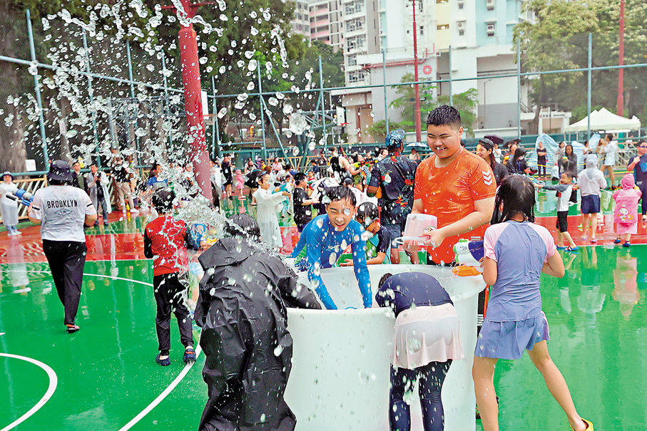 ●市民在雨中利用大水桶提供的「彈藥」展開激烈水戰。 香港文匯報記者北山彥  攝