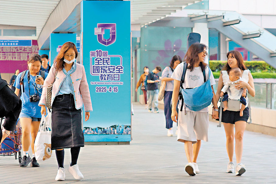 ●第十個全民國家安全教育日宣傳板下,市民掛着歡欣愉快的笑容。 香港文匯報記者北山彥 攝