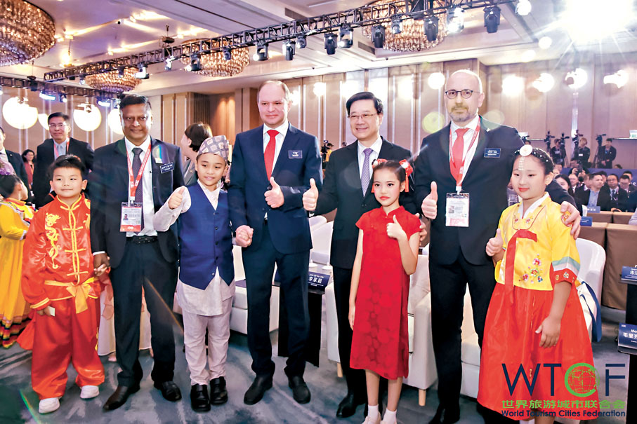 ●「2025世界旅遊城市聯合會香港香山旅遊峰會」昨日在香港開幕，峰會以「創新城市品牌  促進旅遊業高質量發展」為主題。圖為在穿着民族服飾小朋友的引領下，李家超與參會的外國嘉賓步入會場。 受訪者供圖