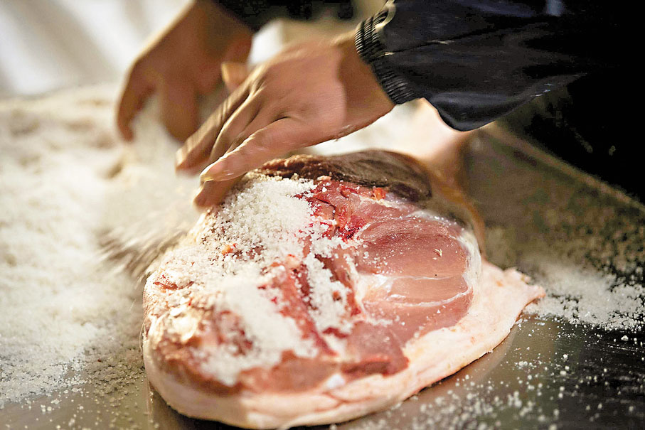 ●工人正以鹽醃製金華火腿。 資料圖片