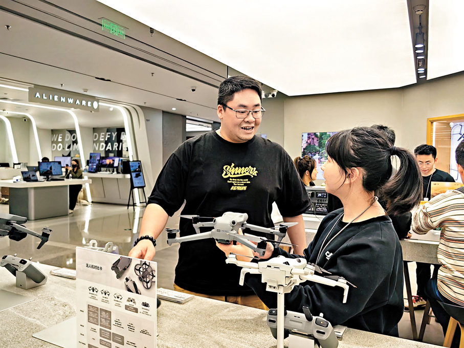●區先生此行購買了兩台大疆無人機,「即買即退」退回現金約1,362.8元人民幣。圖為區先生向大疆店員諮詢產品。 香港文匯報記者郭若溪 攝