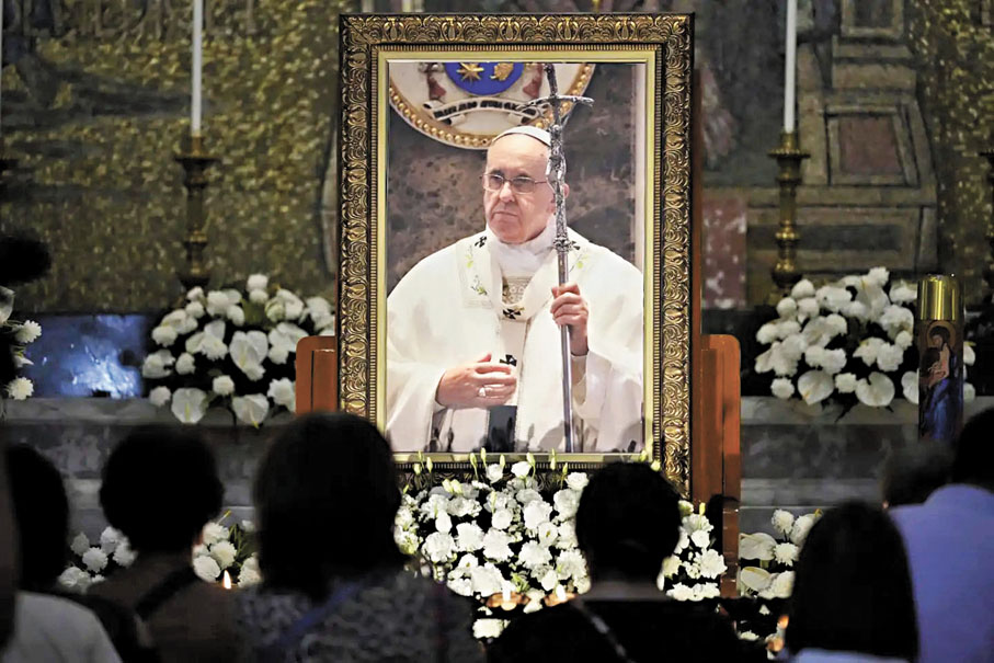 ●菲律賓教徒在已故教宗方濟各的肖像前點燃蠟燭。 美聯社