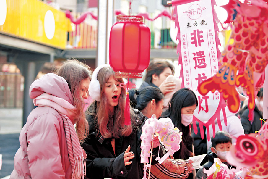 ●早前,兩名外國遊客在山東省威海市環翠區年貨大集上購買非遺龍燈等國貨產品。 資料圖片