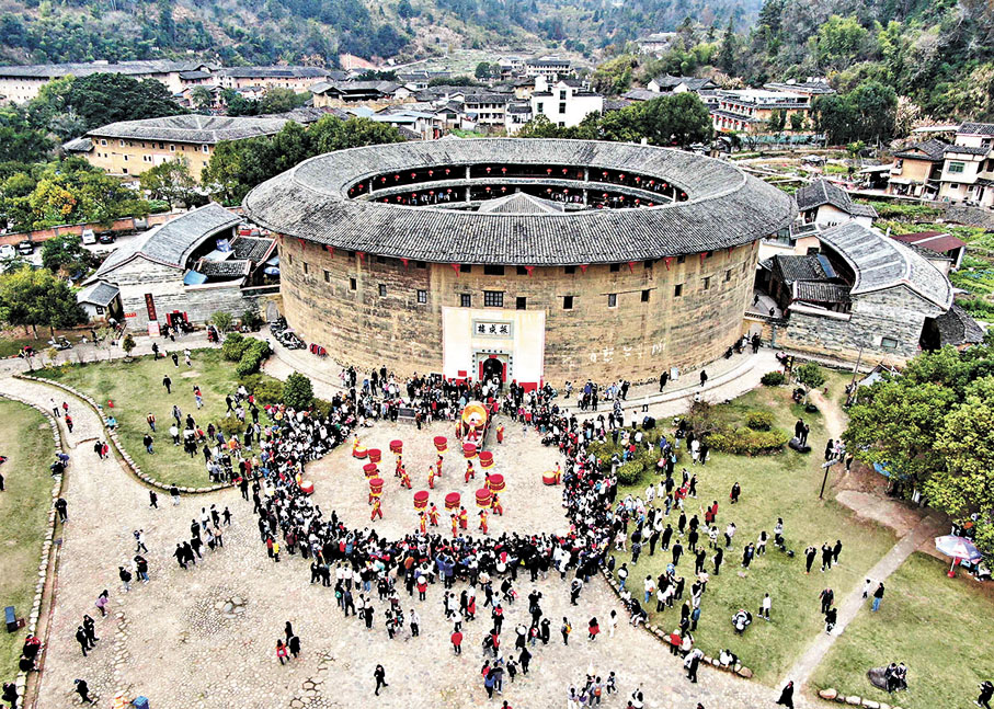 ●客家土樓古樸雄渾。圖為遊客在福建龍岩永定區土樓景區觀看民俗表演。 新華社