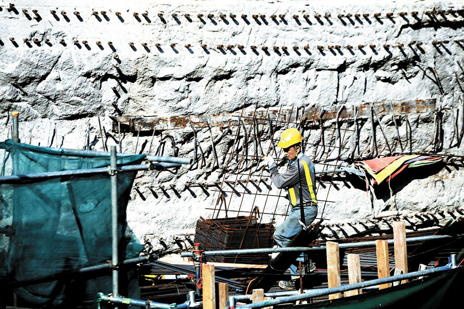 ●地盤工人頂着烈日搬運重物。 香港文匯報記者郭木又  攝