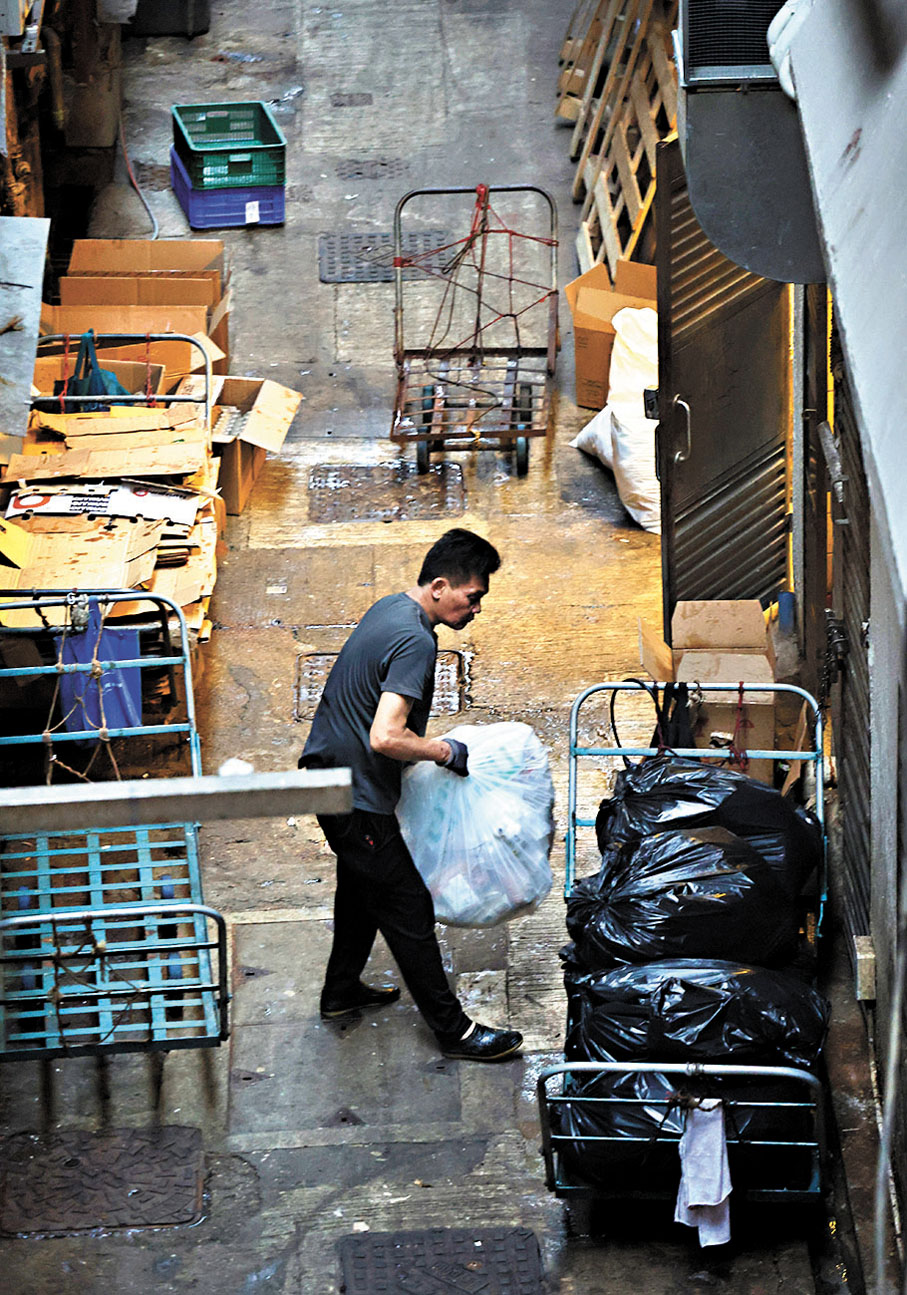 ● 工友在後巷裏清理廢物。 香港文匯報記者曾興偉  攝