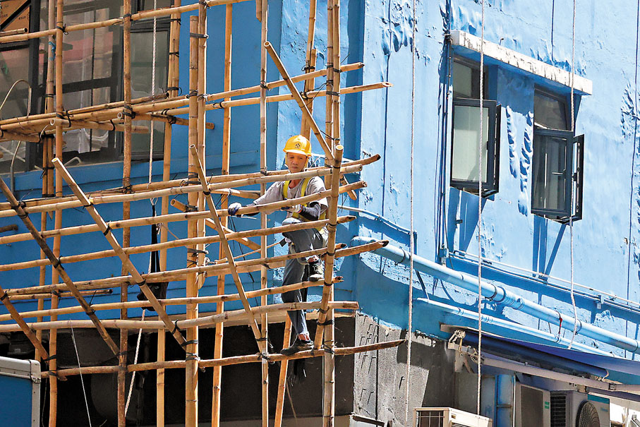 ●工人在棚架上下穿梭，進行大廈外牆修繕工程。  香港文匯報記者萬霜靈  攝