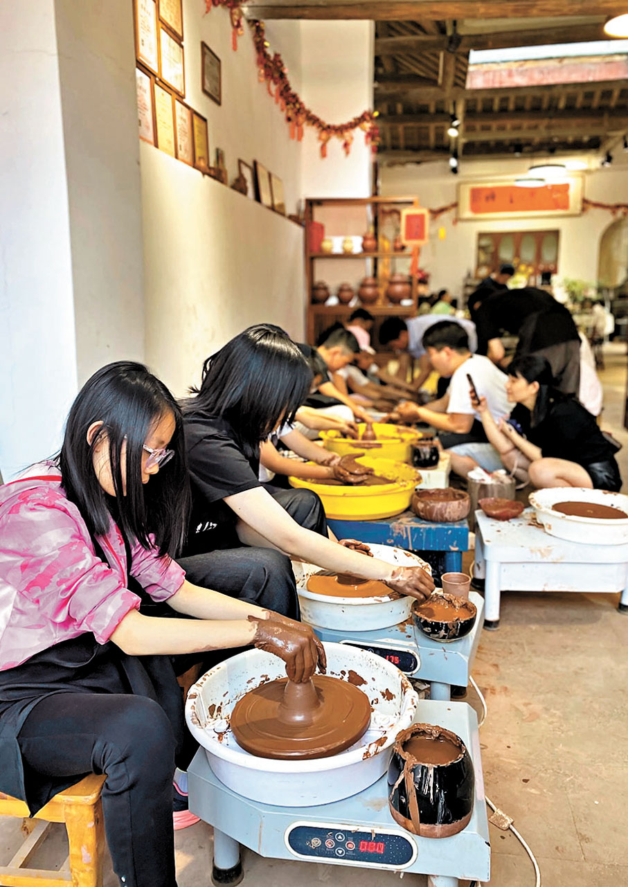 ●從四川成都前來榮昌旅遊的周女士（左二）體驗榮昌陶藝。 香港文匯報記者孟冰  攝