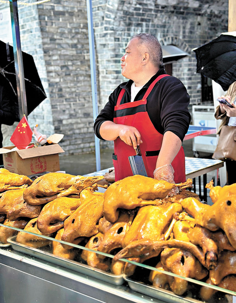 ●榮昌滷鵝因「滷鵝哥」的爆火而廣為人知。圖為當地一名滷鵝店老闆正與遊客攀談。 香港文匯報記者孟冰  攝