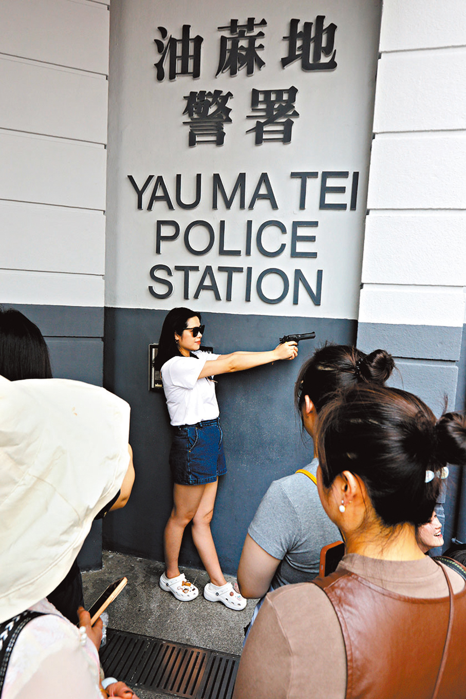 ●旅客到油麻地警署,持道具手槍留影。香港文匯報記者黃艾力 攝