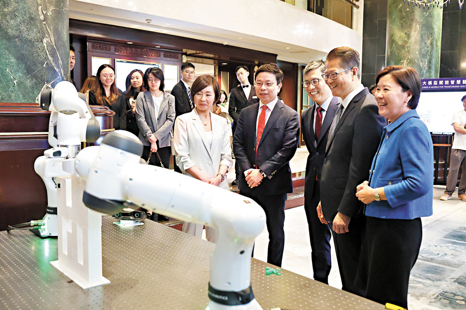 ●賈佳亞(右四)向嘉賓展示由其團隊設計的機械臂。 香港文匯報記者萬霜靈 攝