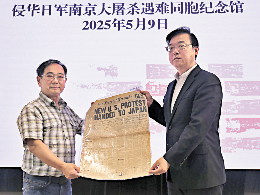 ●魯照寧(左)向侵華日軍南京大屠殺遇難同胞紀念館館長周峰捐助史料。 香港文匯報記者賀鵬飛 攝