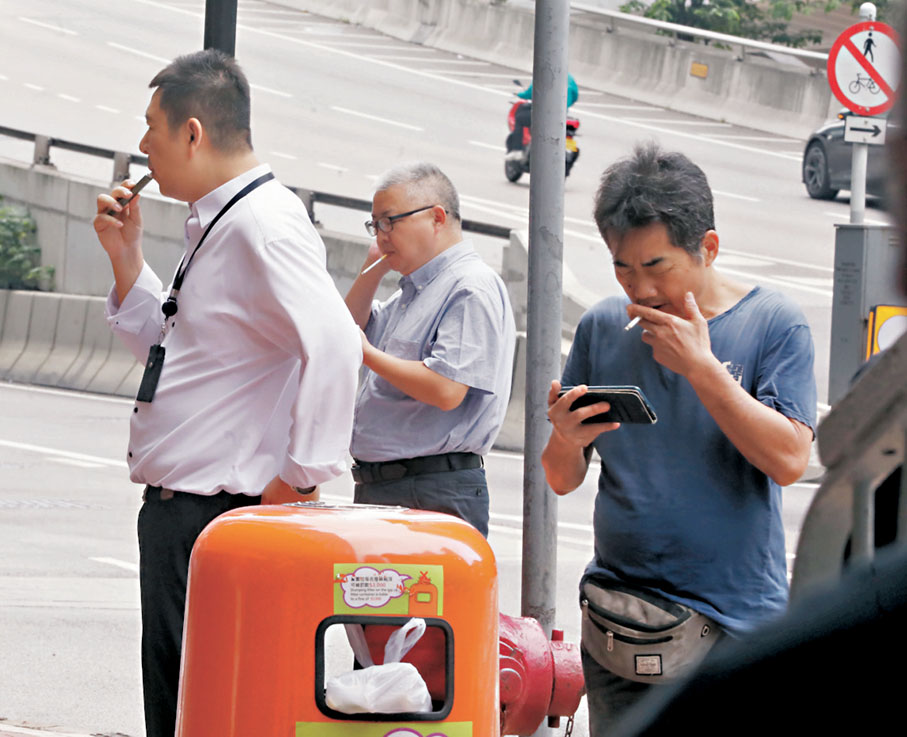 ●圖為煙民在街邊圍着垃圾桶吸煙「打邊爐」。資料圖片