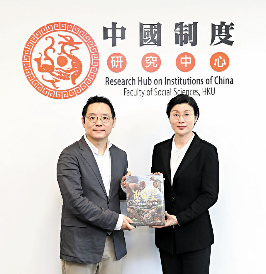 ●關蓉暉(右)向香港大學中國制度研究中心主任閻小駿贈送《遼寧美 1.2億年前的生命奇觀》。特約通訊員陳鴻博 攝