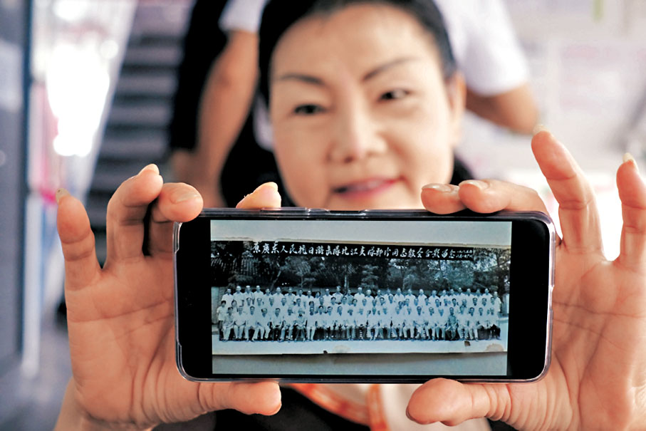 ●余小平展示父親在東江縱隊時的大合照。香港文匯報記者涂穴 攝