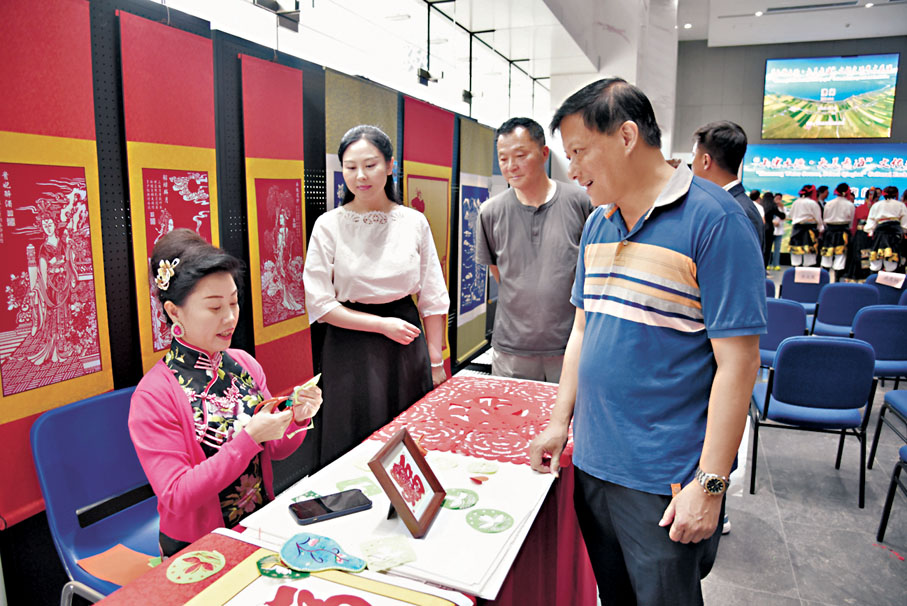 ●青海河湟剪紙傳承人單永武（左一）向澳門市民賴宏（右一）介紹青海剪紙藝術。
