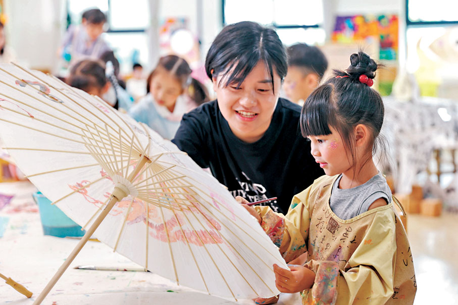 ●5月30日，在浙江省湖州市德清縣鍾管鎮中心幼兒園，老師在指導小朋友畫紙傘度過「六一」國際兒童節。 新華社