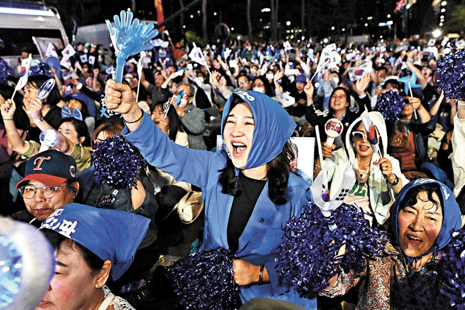 ●李在明支持者獲悉初步點票結果後揮舞國旗慶祝。 路透社