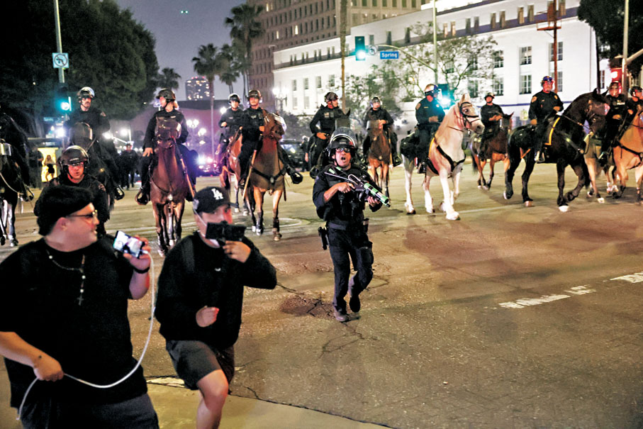 ●洛杉磯中心部分地區實施宵禁,警員驅趕民眾離開。 路透社