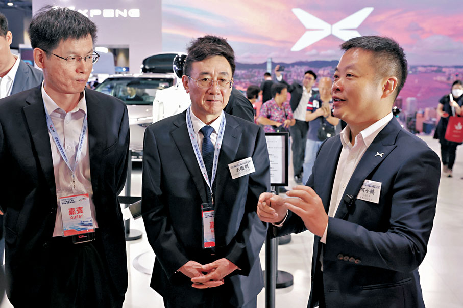●小鵬汽車董事長何小鵬（右一）在展位向嘉賓介紹公司產品。 中通社