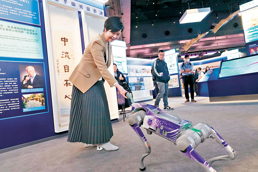 ●何永賢帶隊與同事參觀國安展覽。她認為這些活動可以開拓同事們的認知和眼界,未來都會鼓勵同事積極參與。圖為她和機械狗握手。 受訪者供圖