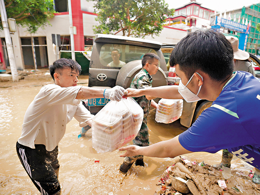 ●6月26日，在貴州省榕江縣城，工作人員將盒飯送到抗洪救災一線。 新華社