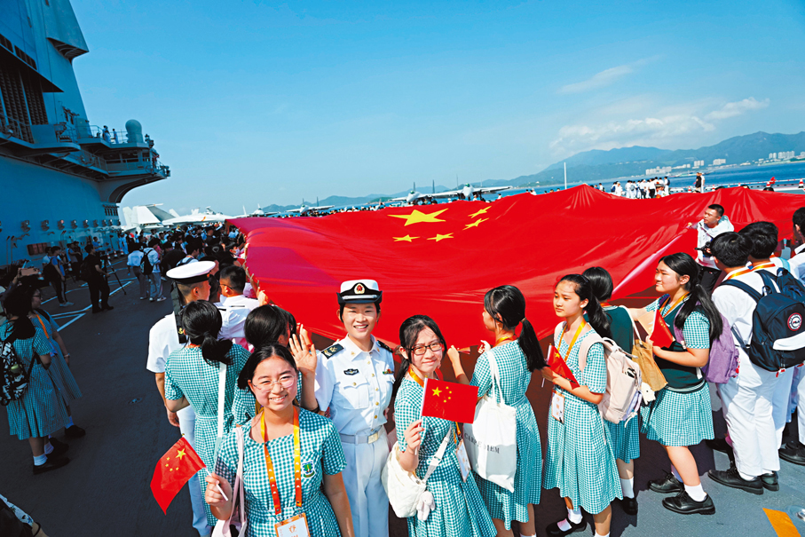 ●山東艦官兵與香港學生在航母甲板上拉開巨幅國旗並同聲高唱《我和我的祖國》。大公文匯全媒體記者蔡文豪 攝