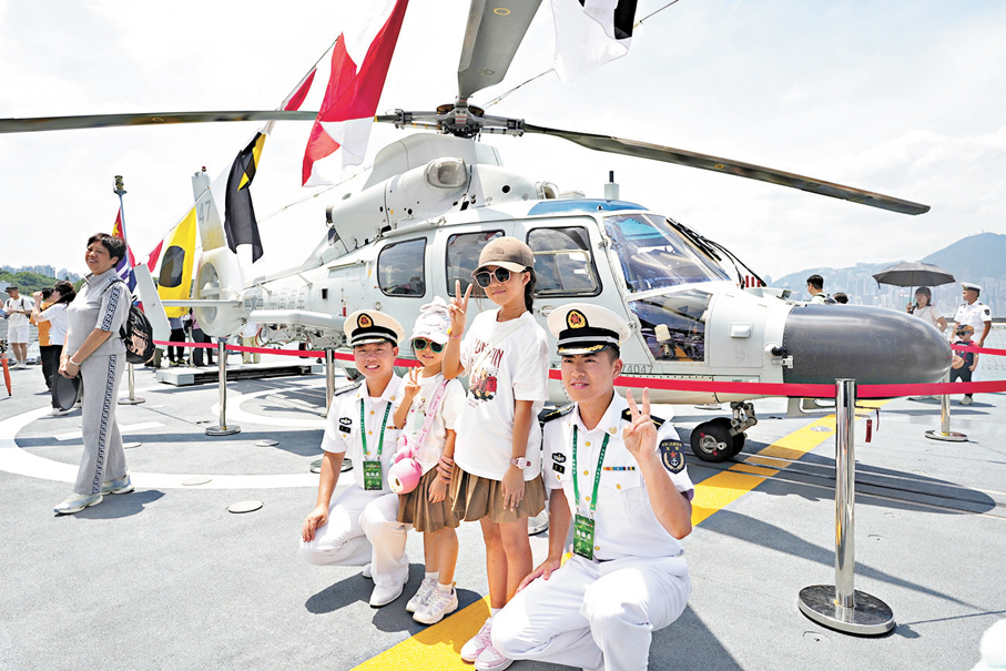 ●兩名女童在艦載直升機前與官兵合照。大公文匯全媒體記者蔡文豪 攝