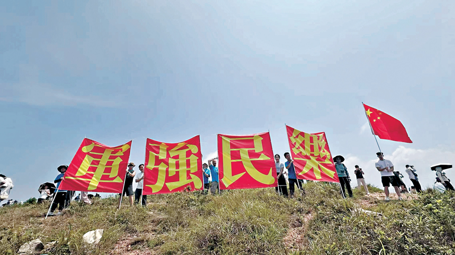●市民登上玉桂山展示「軍強民樂」巨幅標語，歡送山東艦編隊離港。 大公文匯全媒體記者  攝