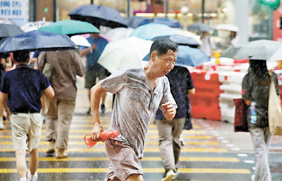 ●無帶雨具的市民在大雨中奔跑避雨。 香港文匯報記者郭木又 攝