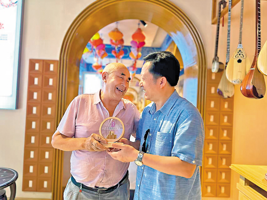 ●香港新聞聯高層參訪團向民族樂器製作者托合提·肉孜贈送紀念品。