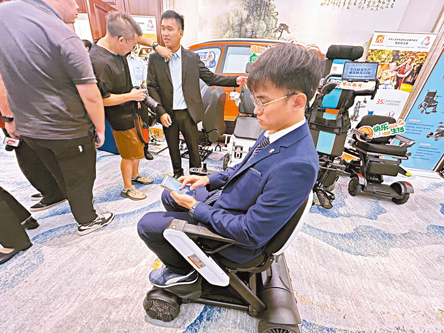 ●現場工作人員展示用手機控制自動摺疊電動輪椅，它將投放於香港賽區。
