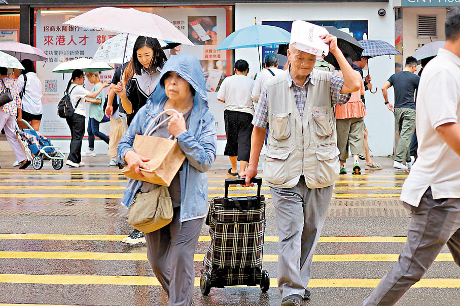 ●香港天文台昨日上午發出黃色暴雨警告信號，大雨下沒帶傘的市民，只好拿着紙盒擋雨。 香港文匯報記者北山彥  攝