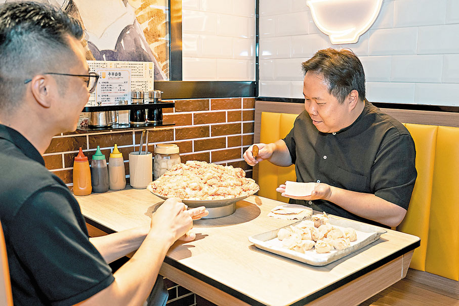 ●蕭欣浩（右）向十大碗粥舖專家傳人劉家樂學包雲吞。 作者供圖