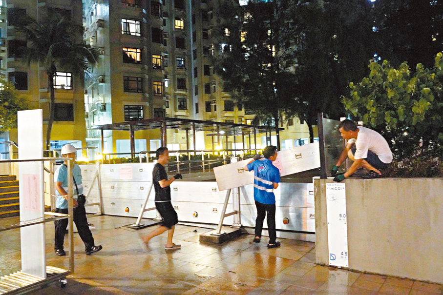 ●康文署工人昨晚冒雨在杏花邨海旁安裝防水閘。 香港文匯報記者曾興偉  攝