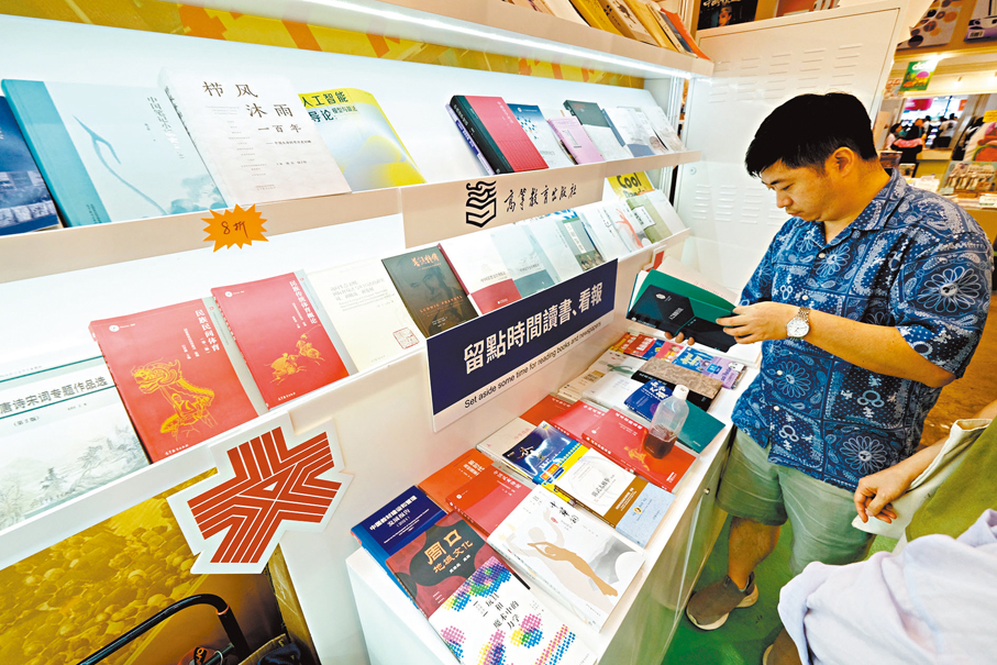 ●市民在大公文匯傳媒集團的展攤細閱書籍。 香港文匯報記者涂穴  攝