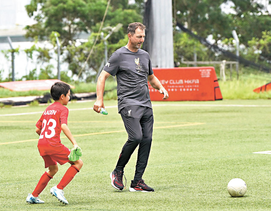 ●球員年代司職門將的杜迪克（右）昨日客串場區球員與小球員交流。  香港文匯報記者張發兒  攝