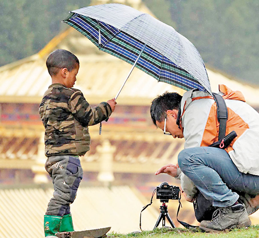 ●藏族小孩幫拍攝中的呂鳳霄打傘。