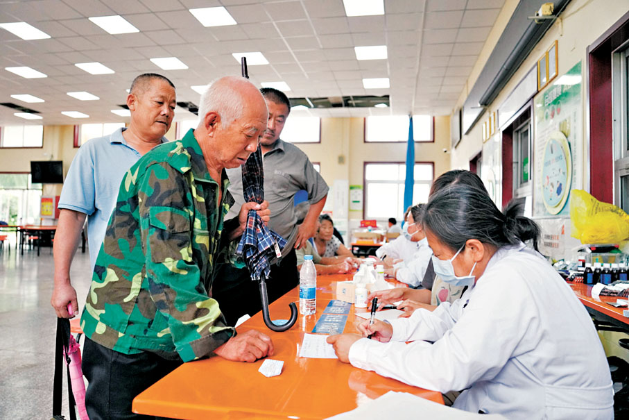 ●7月29日，在北京市密雲區太師莊中學居民安置點，太師屯鎮社區衞生服務中心的醫生（右）為安置在此的群眾開藥。 新華社