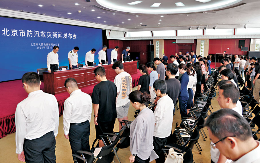 ●7月31日，北京市防汛救災新聞發布會現場，全體起立，向遇難人員默哀。  香港文匯報北京傳真