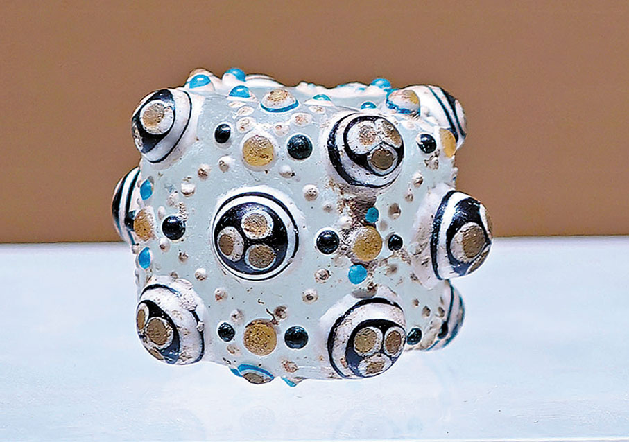 ●堆鑲彩料筒形白料珠，戰國製。這種料珠在中國古代俗稱「蜻蜓眼」。