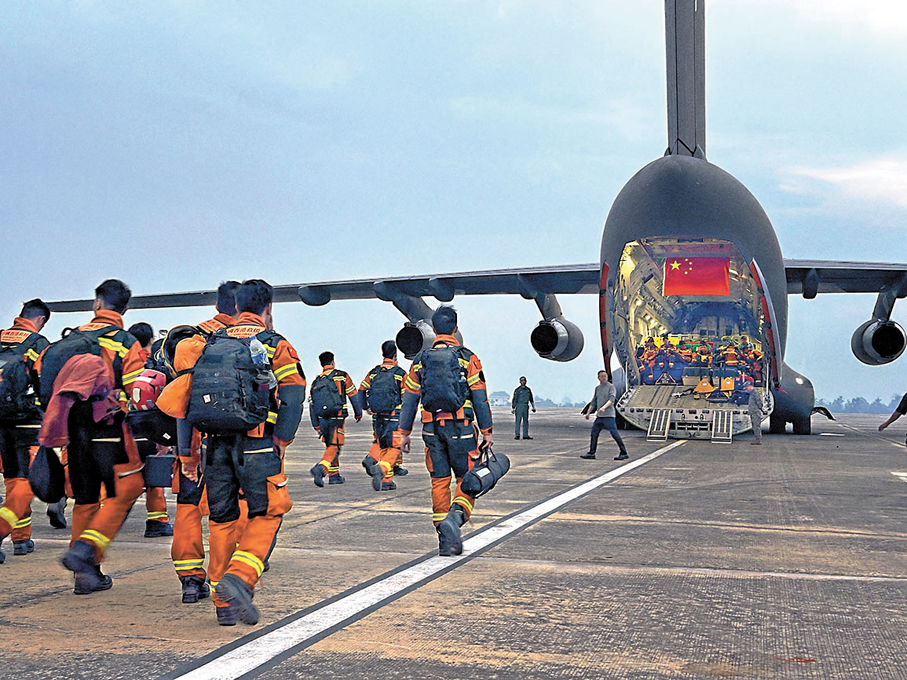 ● 完成任務的救援隊，回程步向掛着五星紅旗的軍機。 消防處圖片