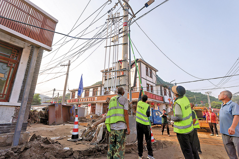 ●截至目前，北京受災行政村供電、通信全部恢復，供水問題已全部解決。圖為8月1日，北京市密雲區馮家峪鎮，通信搶修人員架設新的光纜。  中新社