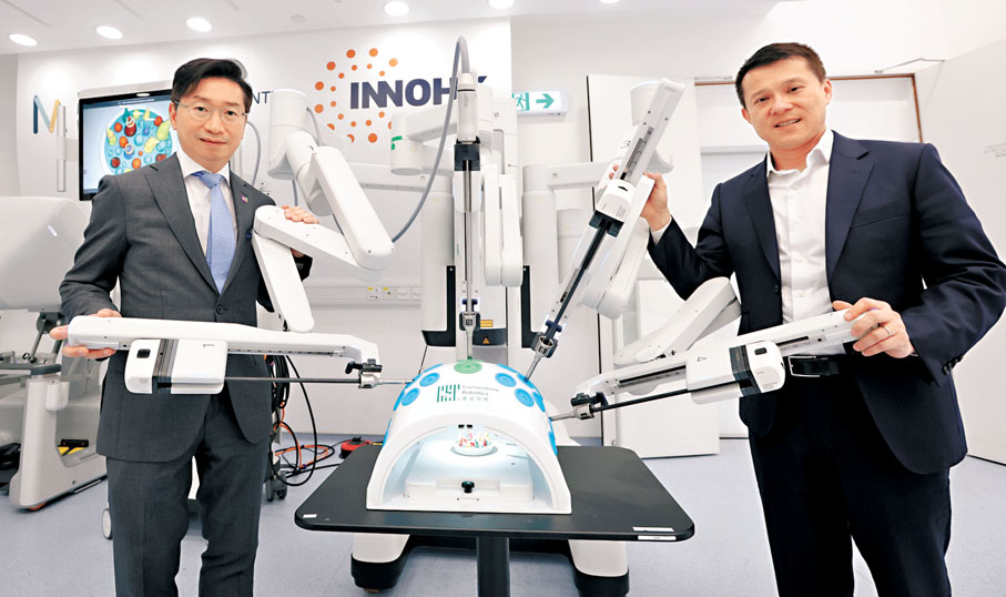 ●歐國威（右）與團隊研發的「Sentire思騰腔鏡手術機械人」，是港自主研發最複雜的機械輔助手術平台。趙偉仁（左）表示，系統借助高清3D影像及高靈活度機械臂，提升手術安全性和效率。香港文匯報記者曾興偉  攝